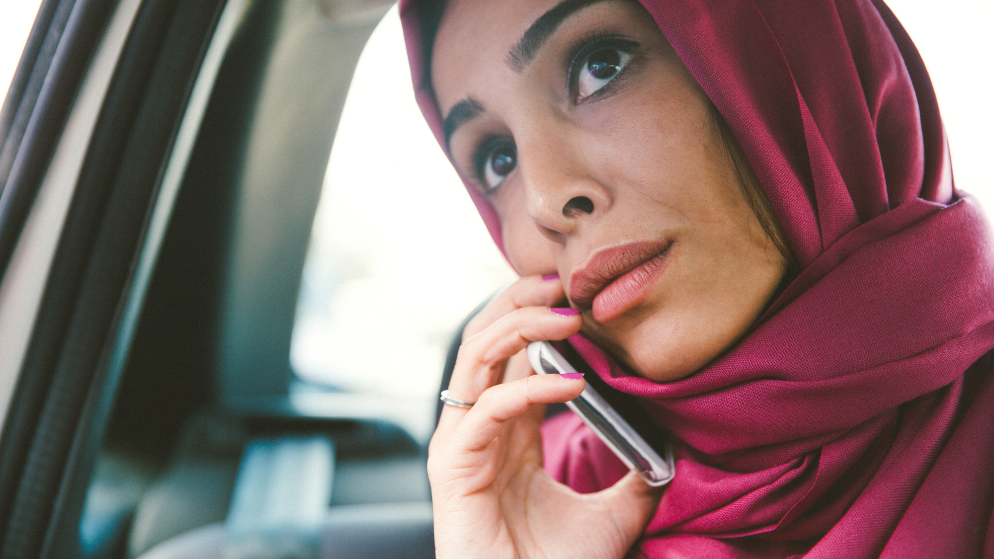 Woman wearing red hood on phone in car
