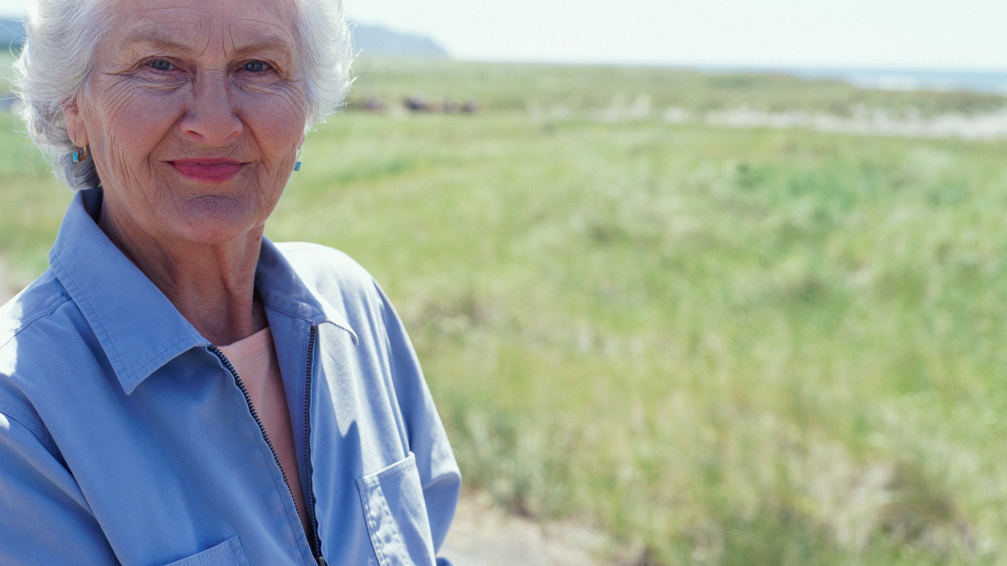 White haired woman stands in pasture