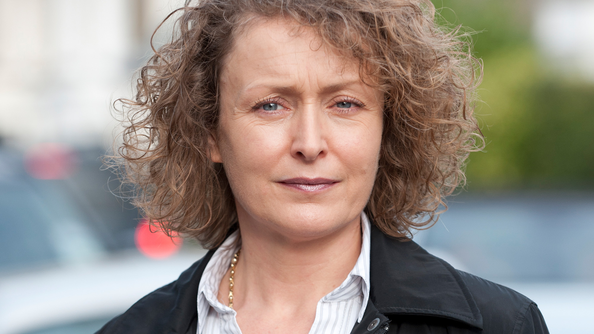 Middle aged woman with curly hair stares ahead