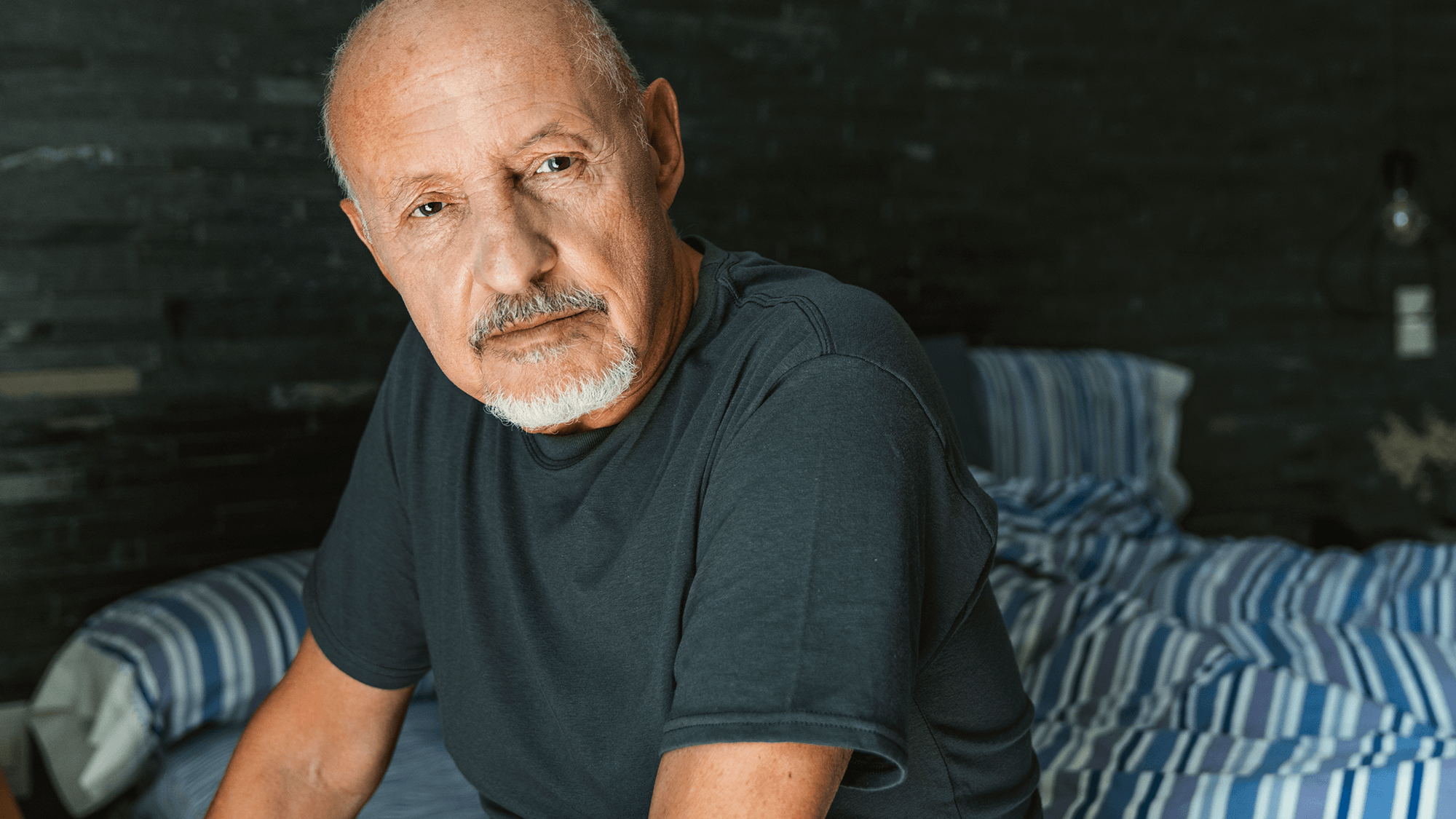 Older man sitting on a bed