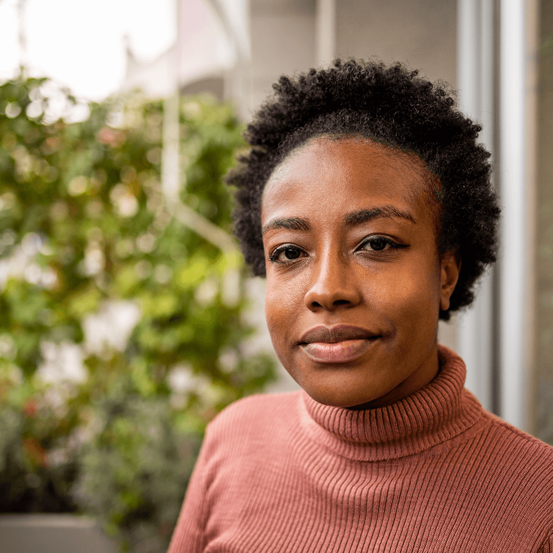 30 Something African American Woman with short black hair and a pink turtleneck