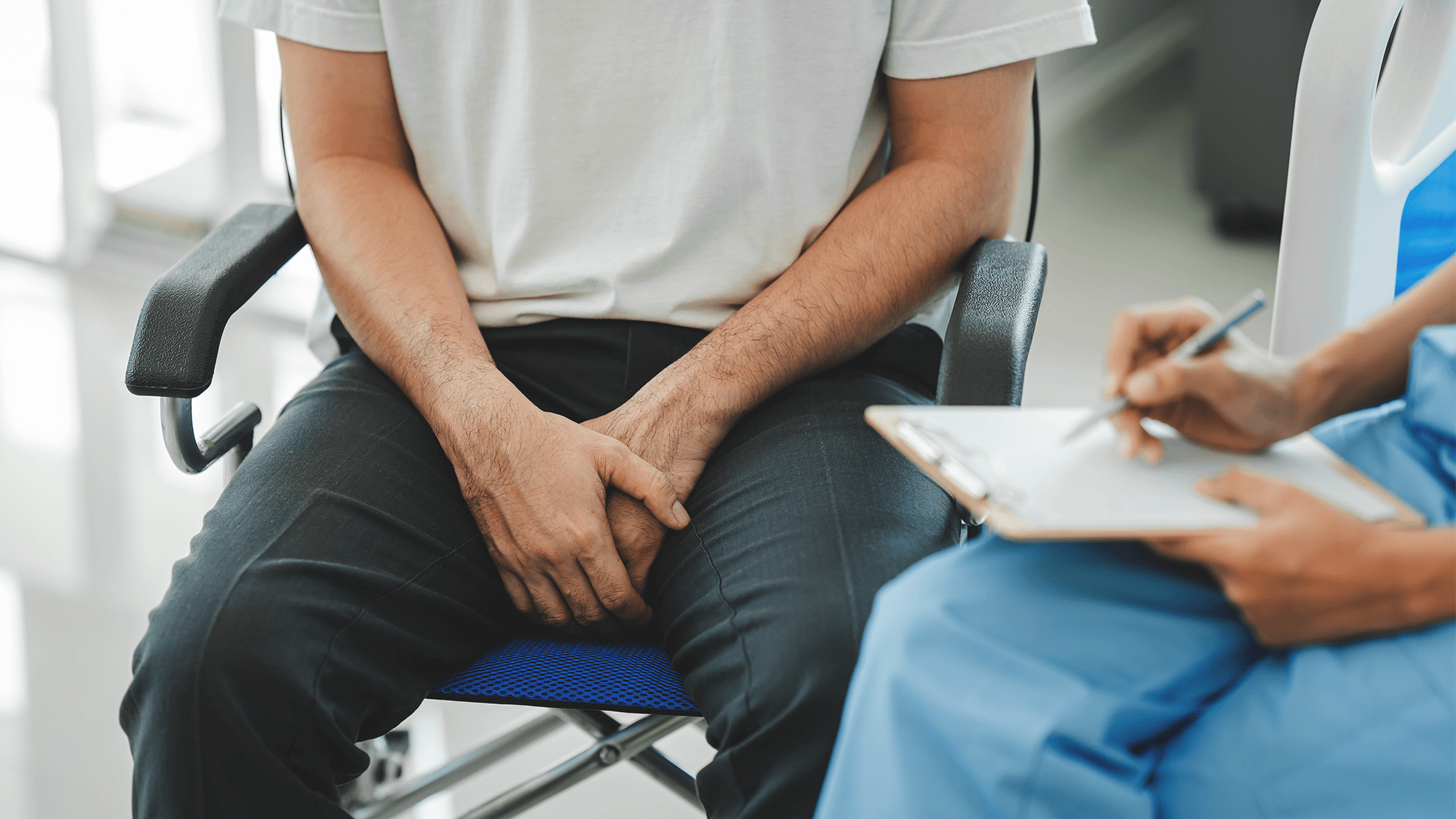 rectangle shaped image of bottom half of doctor and male patient sitting together