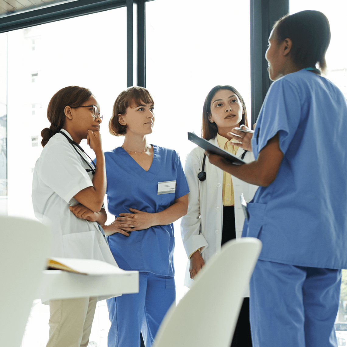 three clinicians getting an update for a doctor in a meeting room area